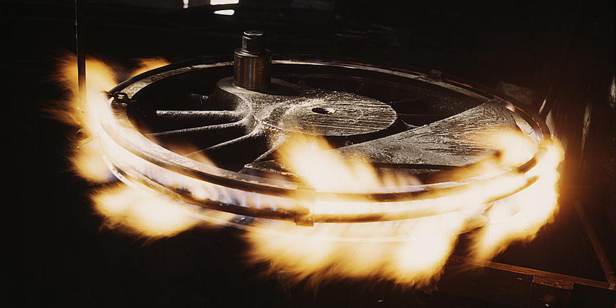 A photo of a train wheel being forged surrounded by flames.