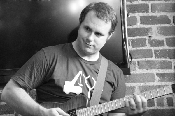 Black and white photo of Vic with headless guitar