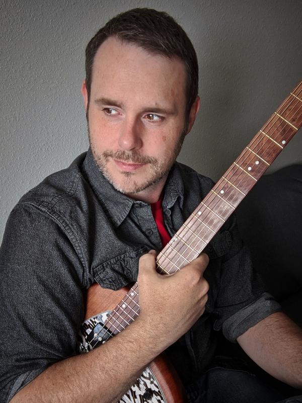 Portrait of Vic Dillahay holding a guitar